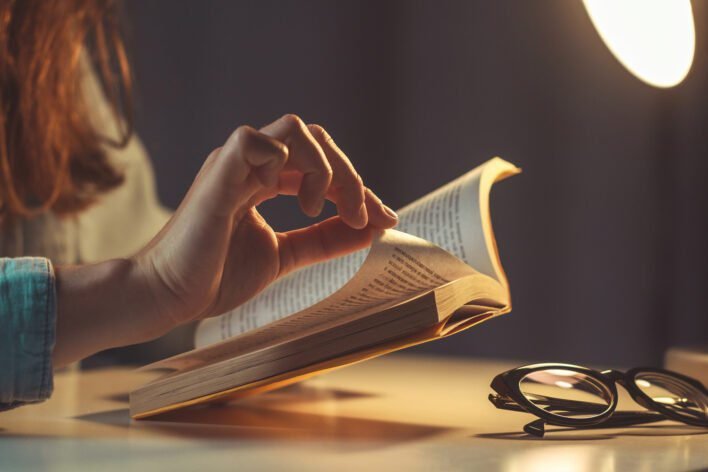 woman reading book evening home close up